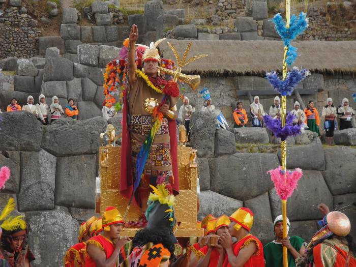 A group of men carrying the Inca with a stone fortress as backdrop