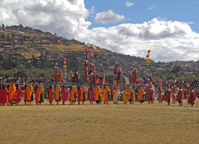 Men and women wearing typical attires surrounding a stage featuring a man and its entourage